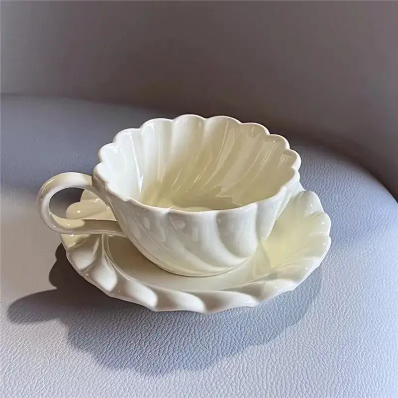 Cream-colored elegant lace ceramic coffee cup and scalloped saucer set for white and mint dining room use