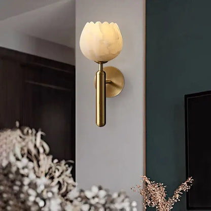 Elegant warm-toned opaline lotus-shaped wall lamp with brushed brass finish and marble wall mounting for bedroom