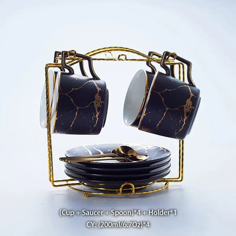 Elegant black marble ceramic tea set with gold veining, matching saucers, and spoons in a gold metal holder