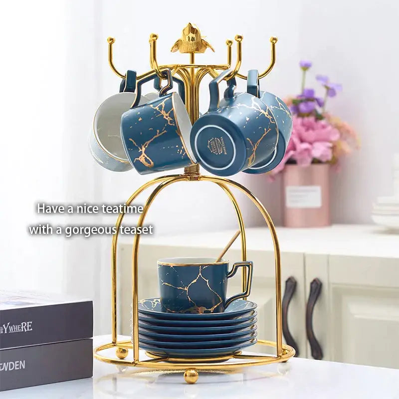 Elegant marble ceramic tea set featuring blue ceramic teacups with gold patterns and matching saucers on a golden stand