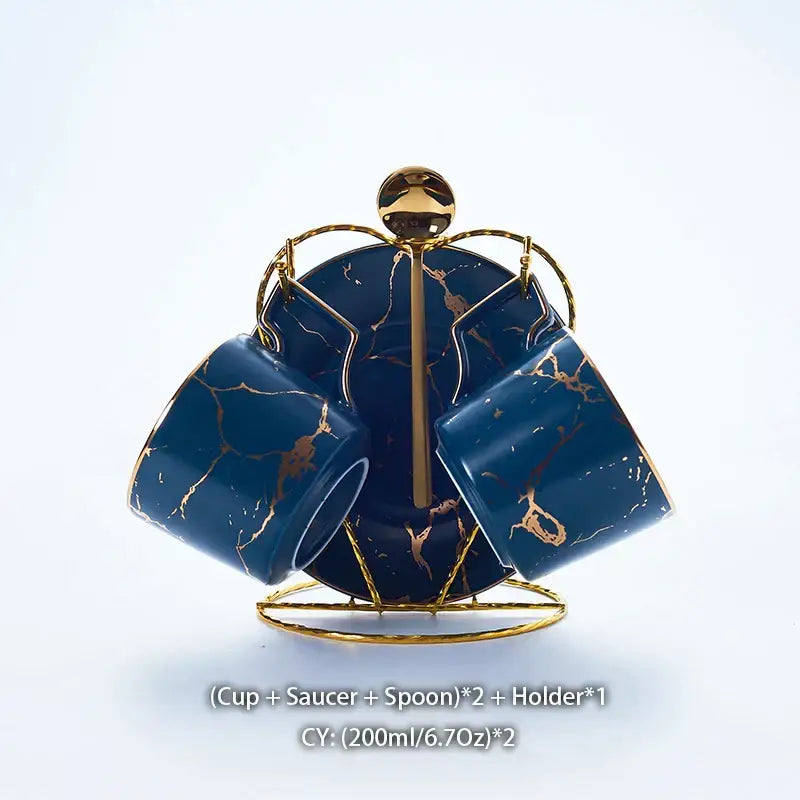 Elegant marble ceramic tea set featuring deep blue mugs with gold veining displayed on a golden metal stand