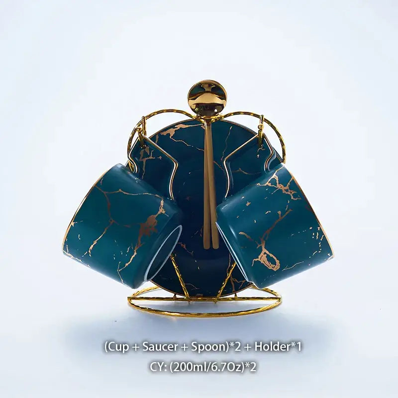 Elegant marble ceramic tea set with teal marble-patterned cups, gold accents, saucers, and spoons on a gold holder