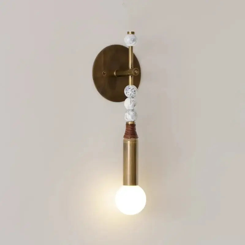 Elegant marble copper wall lamp with brass beads and white marble accents on warm-toned circular backplate for living room decor