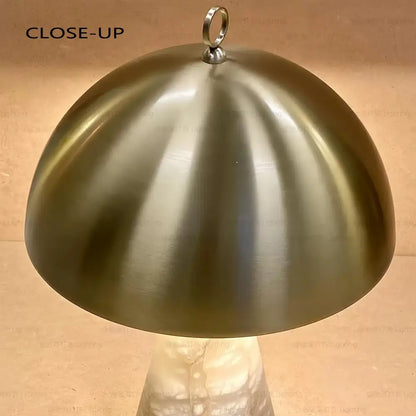 Elegant natural marble table lamp with a brushed brass dome-shaped lampshade and polished metallic ring by decorbites