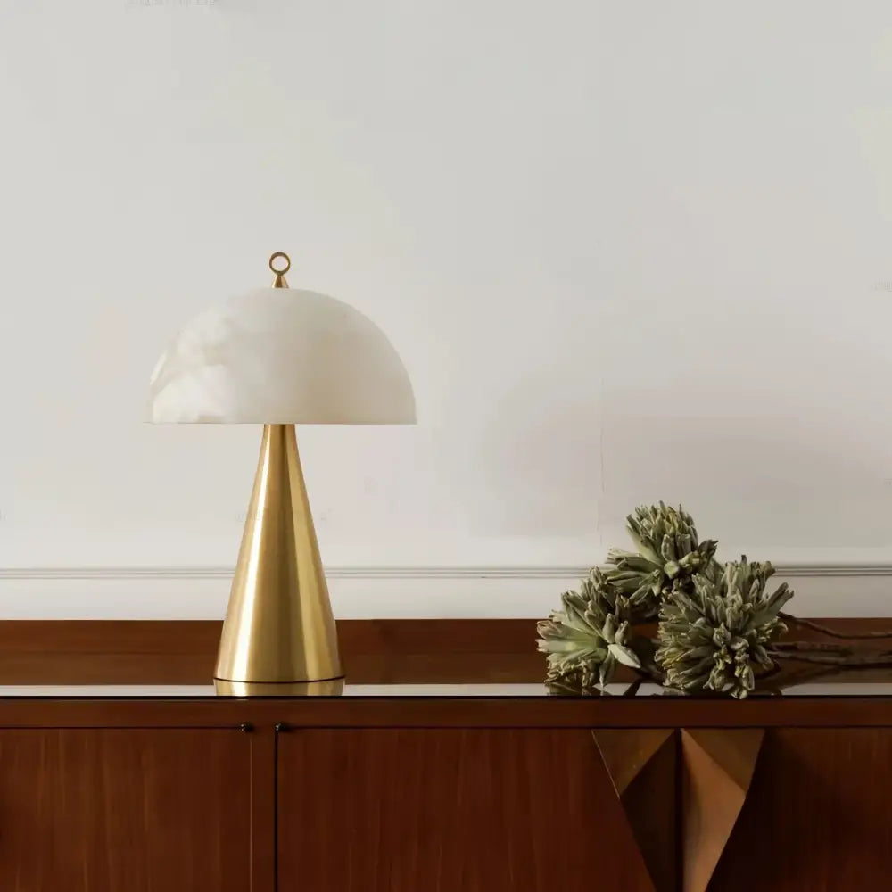 A sleek brass table lamp with an elegant natural marble base and smooth white dome shade for bedroom decor