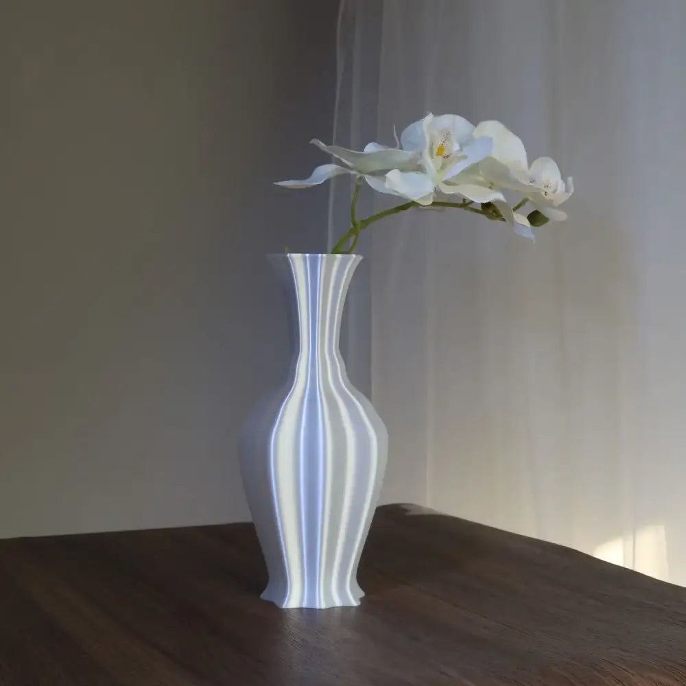 A sleek white ceramic decorbites elegant high-end vase with vertical ridges holding white orchids for living room decor