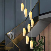 A decorbites elegant tulip staircase chandelier with seven warm-toned tulip-shaped frosted glass pendant lights and gold hardware