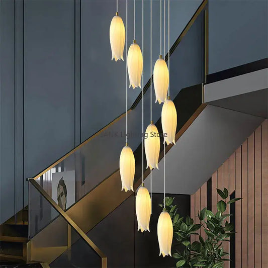 A decorbites elegant tulip staircase chandelier with seven warm-toned tulip-shaped frosted glass pendant lights and gold hardware