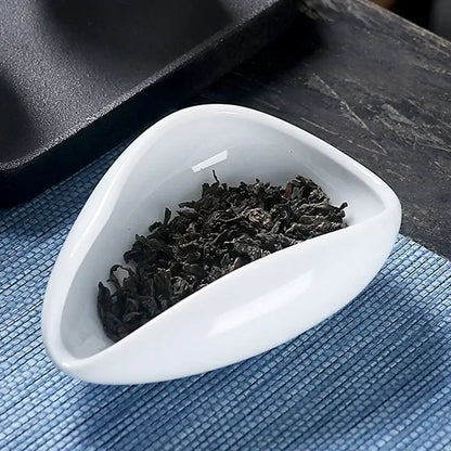 A sleek white ceramic dose tray with a tea spoon filled with dark curly loose-leaf tea decorbites ceramic white