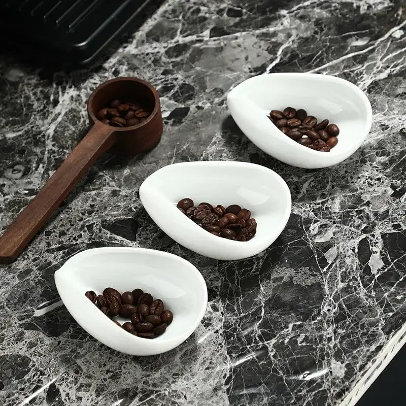 Elegant white ceramic dose trays with dark roasted coffee beans and a tea spoon from decorbites ceramic white set