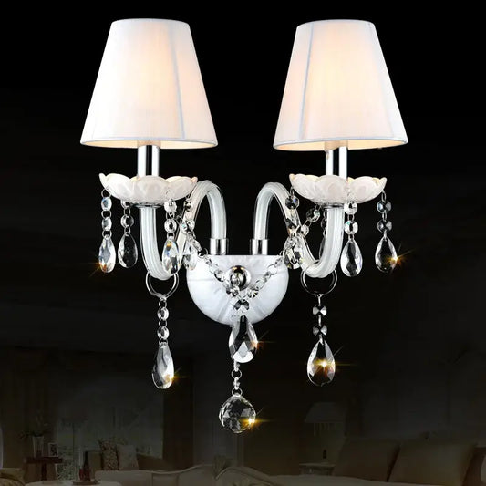 Elegant white crystal wall lamp with double fabric shades and dangling teardrop crystals for bedroom decorbites crystal wall lamp