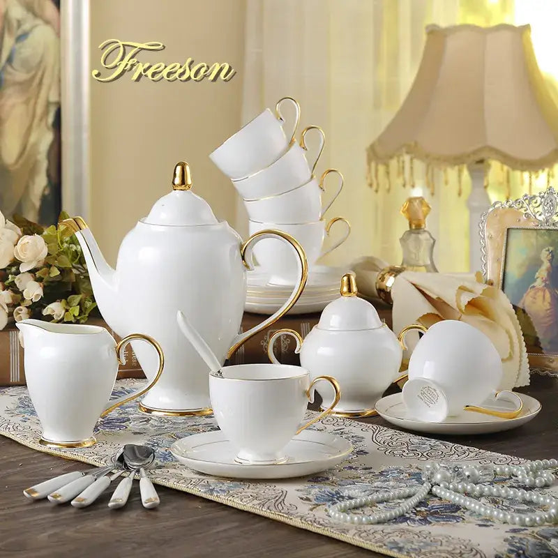 Elegant white and gold bone china coffee set with curved handles including sugar bowl creamer and stacked cups