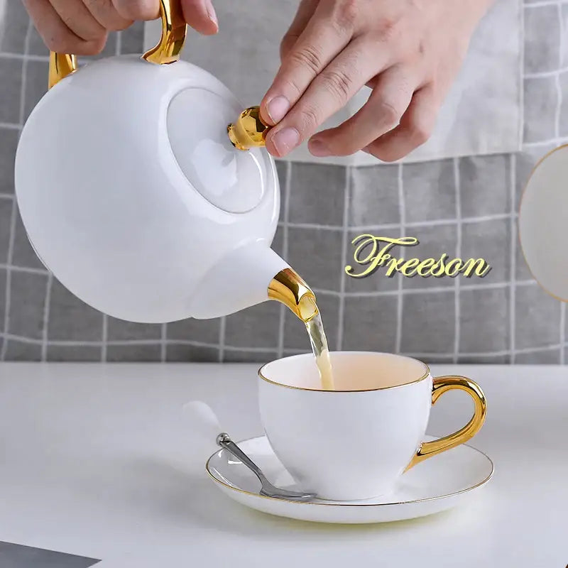 White ceramic teapot with gold accents pouring into matching cup from decorbites elegant bone china tea set