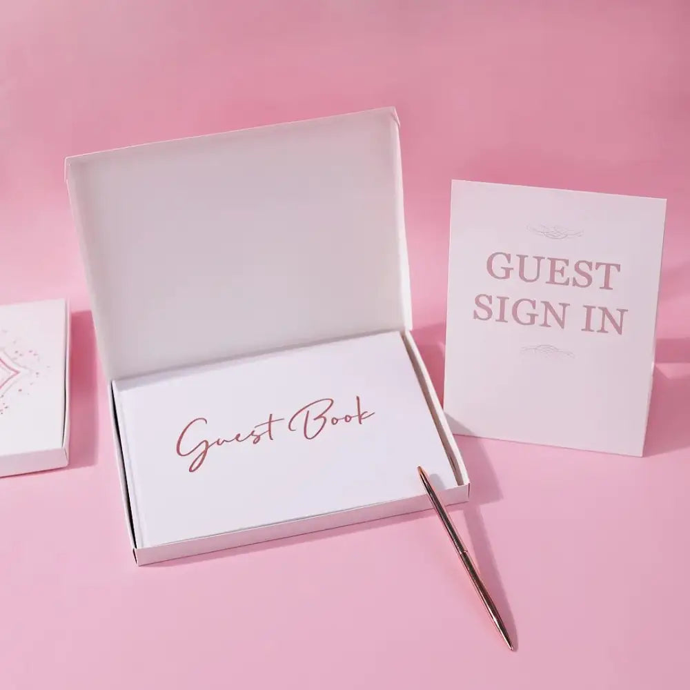 Elegant white guest book with rose gold bronzing detail by decorbites, displayed open with a pen and guest sign in card