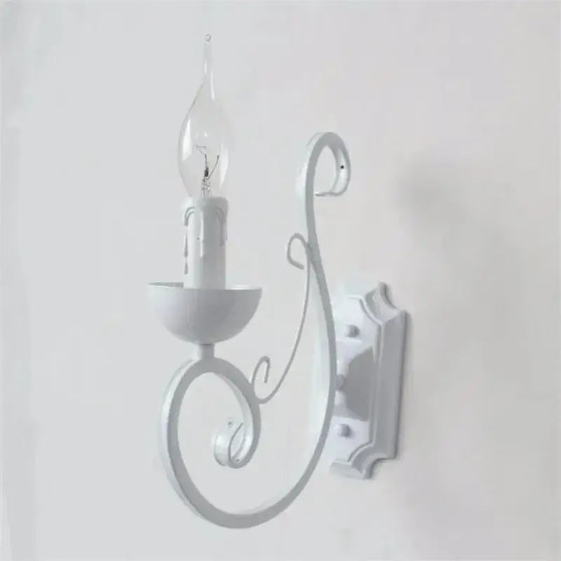 Elegant white iron wall lamp with ornate scrollwork and clear glass candle-style bulb by decorbites wall lamp
