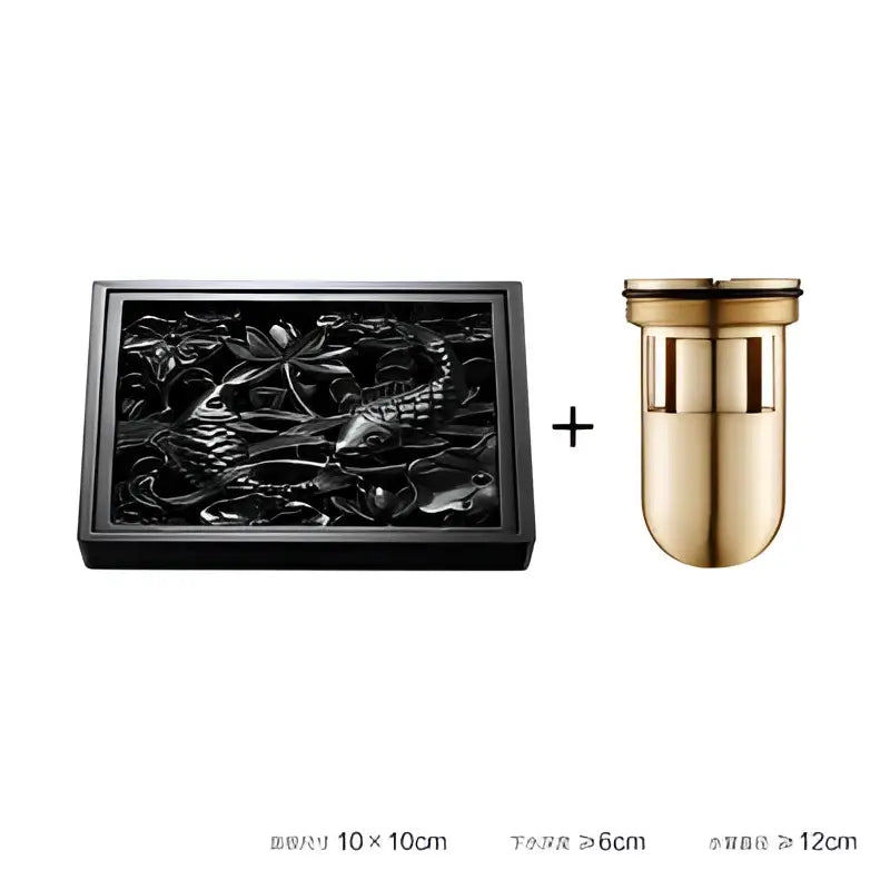 Black brass square floor drain with embossed lotus and fish design paired with gold-toned water filter for shower room
