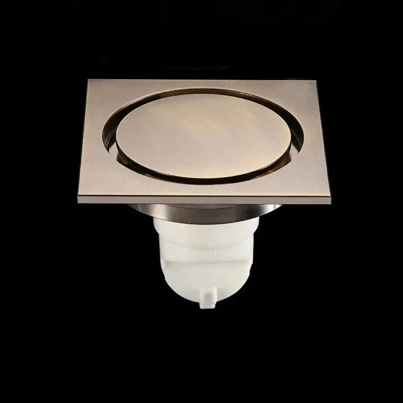 Embossed floral black brass square floor drain with brushed stainless steel circular center and white plastic base for shower room