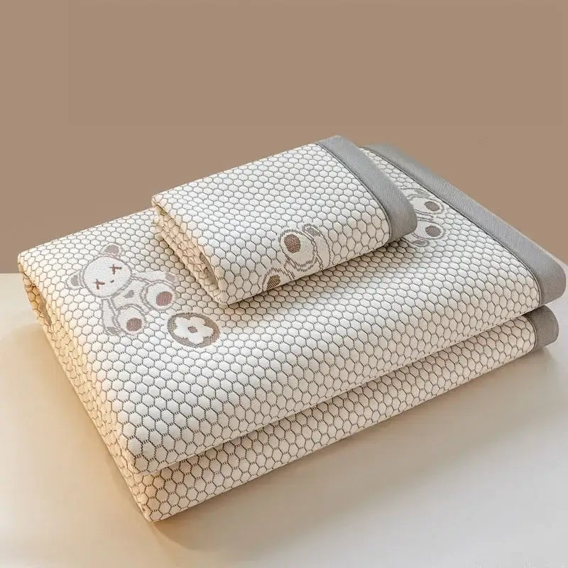 White and gray honeycomb-patterned cooling feel mat with embroidered cartoon bear faces in mat set for bedroom mattress
