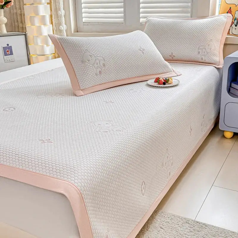 Pink-edged white textured cooling feel mat set with embroidered bear designs for bedroom mattress use