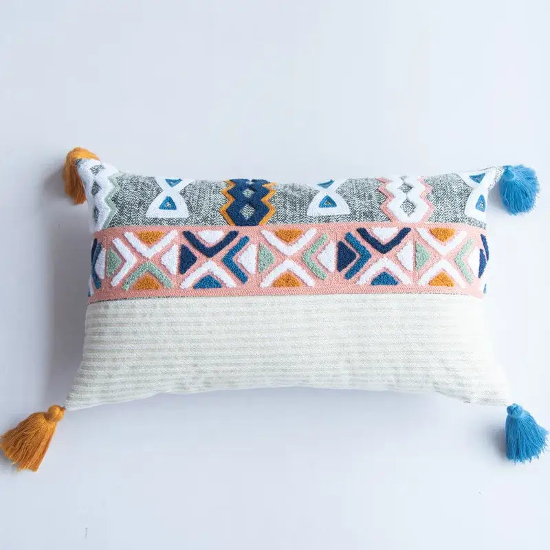 Rectangular pillow cover with embroidered blue tufted geometric patterns in gray orange and pink on textured fabric with tassels