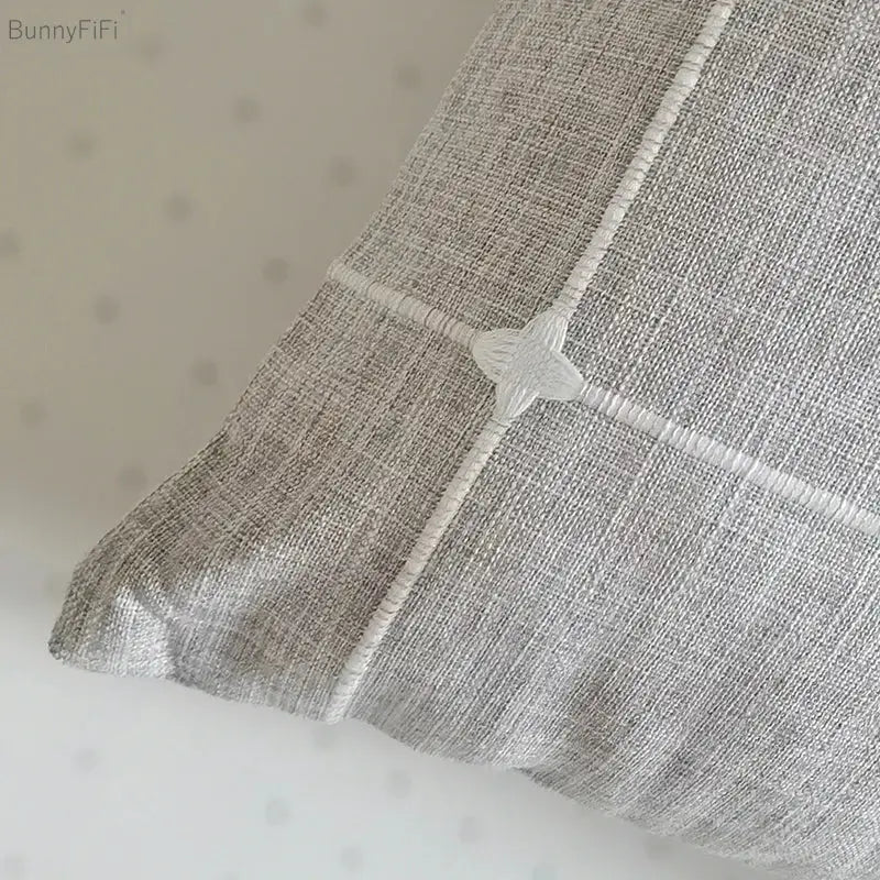 Gray linen pillow with white stitched grid and star button featuring brown grey stripe embroidery for decorbites brown grey decor