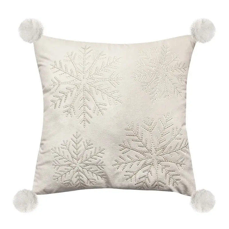 Cream-colored pillow cover with four embroidered silver snowflakes and white pom-poms for decorbites embroidered christmas decor