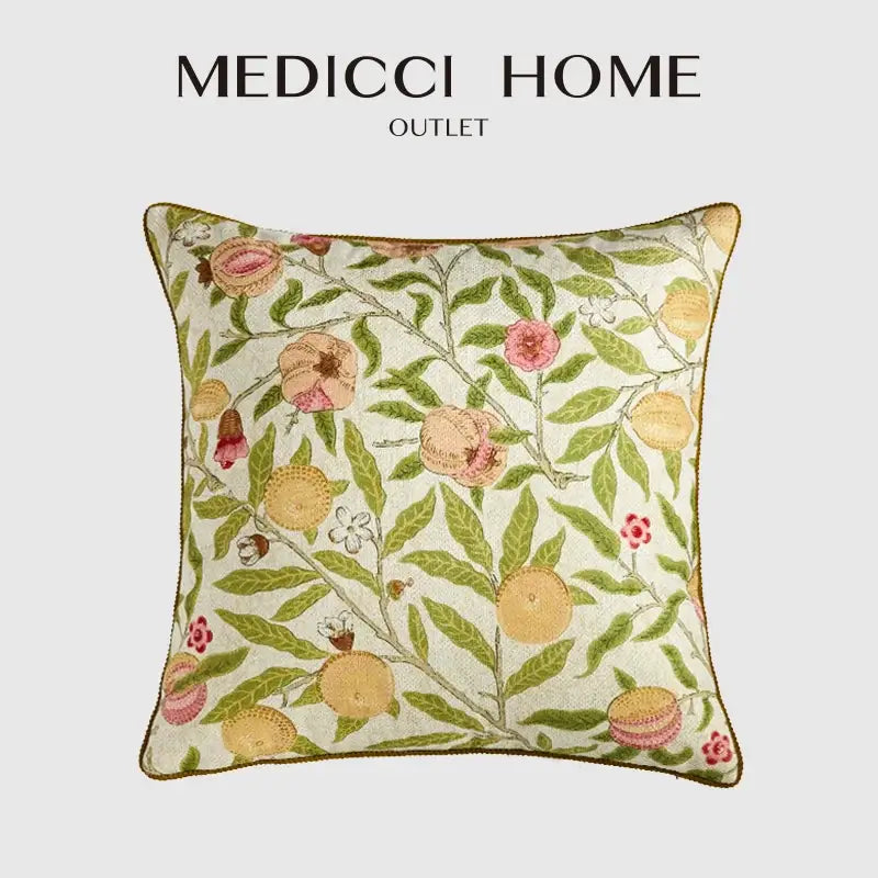 A cream-colored embroidered pillow case with decorbites citron flowers plants featuring pink and yellow fruits and gold-brown trim