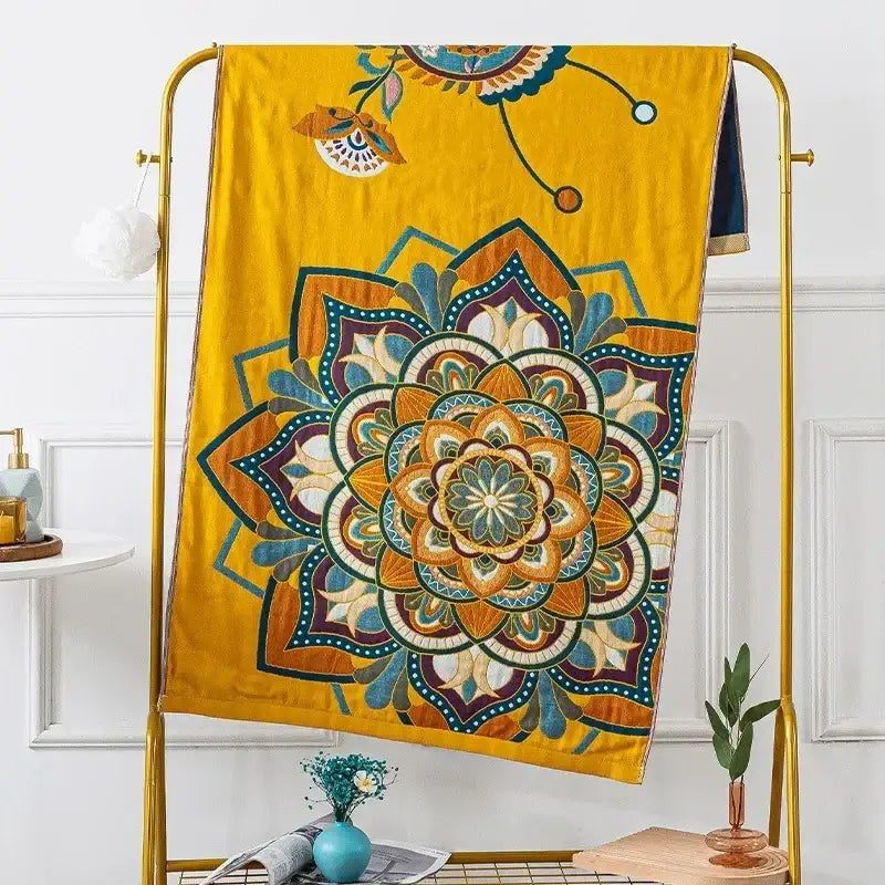 A vibrant yellow decorbites cotton gauze bath towel with an embroidered multicolored mandala design for bathroom decor