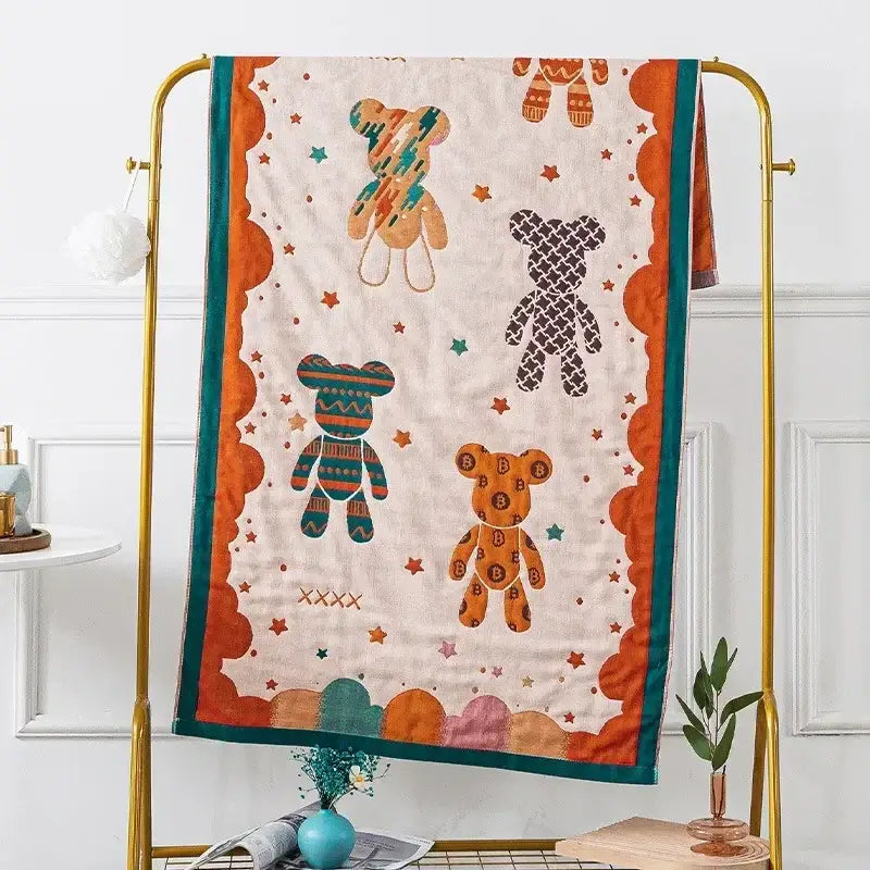 Cream-colored quilted cotton gauze bath towel with playful orange and teal teddy bear designs for bathroom decor