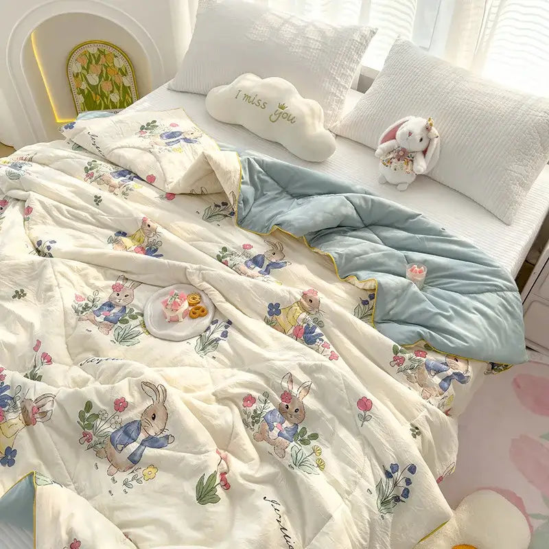 A soft off-white double gauze quilt with embroidered rabbit print in blue outfits surrounded by colorful flowers