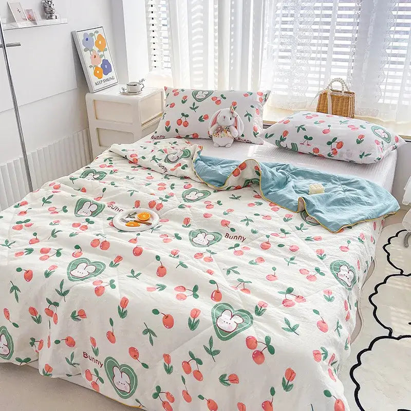 White quilted double gauze comforter with embroidered rabbit print and playful cherry pattern in soft pastel colors