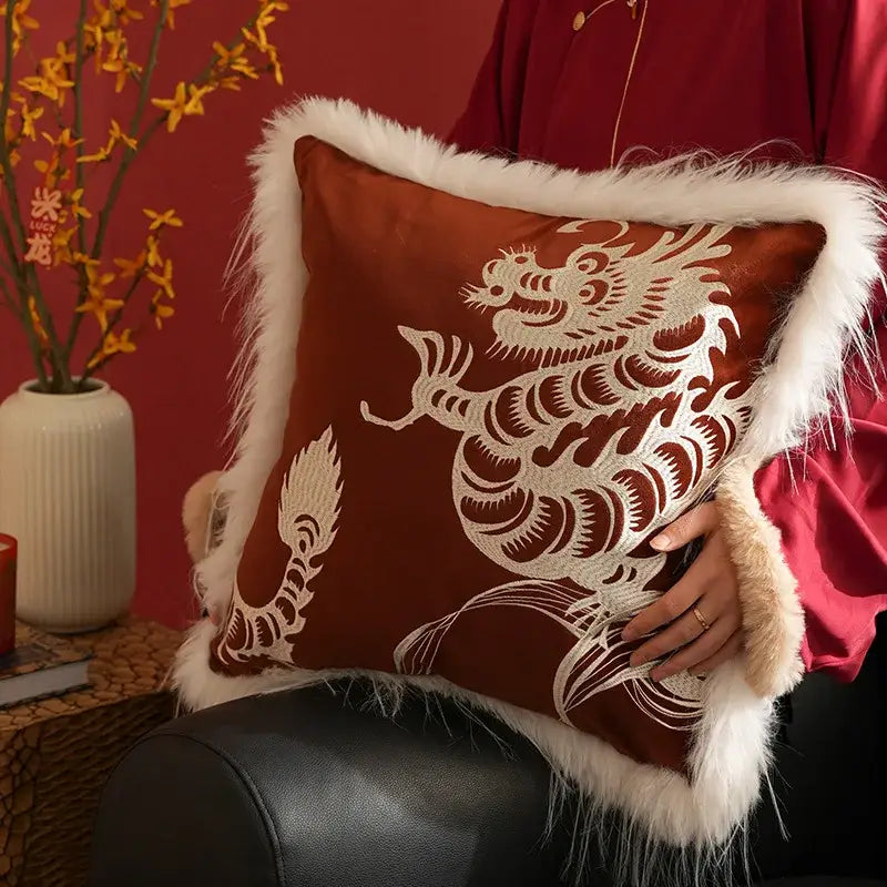 A rust-colored embroidered dragon year pillowcase with white dragon year decorbites design and fluffy white fur trim