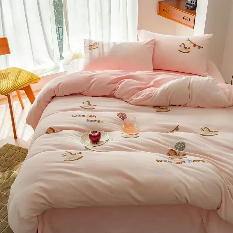 Pink plush embroidered fleece winter bedding set with wooden horse designs and colorful thread text in cream bedroom