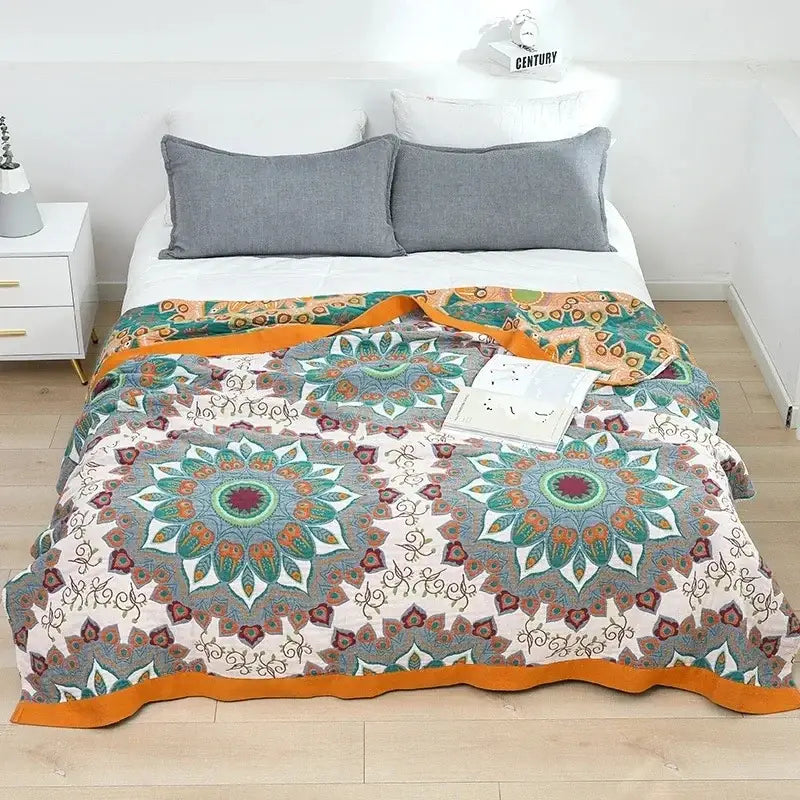 A cozy decorbites cotton gauze bedroom blanket with teal orange cream mandala patterns and a vibrant orange border