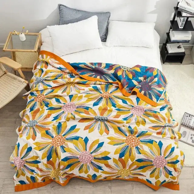A vibrant embroidered floral blue and cream decorbites cotton gauze bedroom blanket with yellow blue and pink blossoms