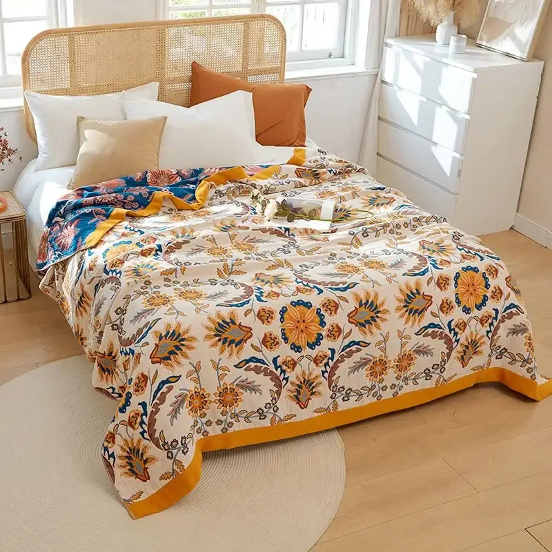A cozy cream decorbites cotton gauze throw blanket with vibrant orange blue brown floral pattern and mustard-yellow border