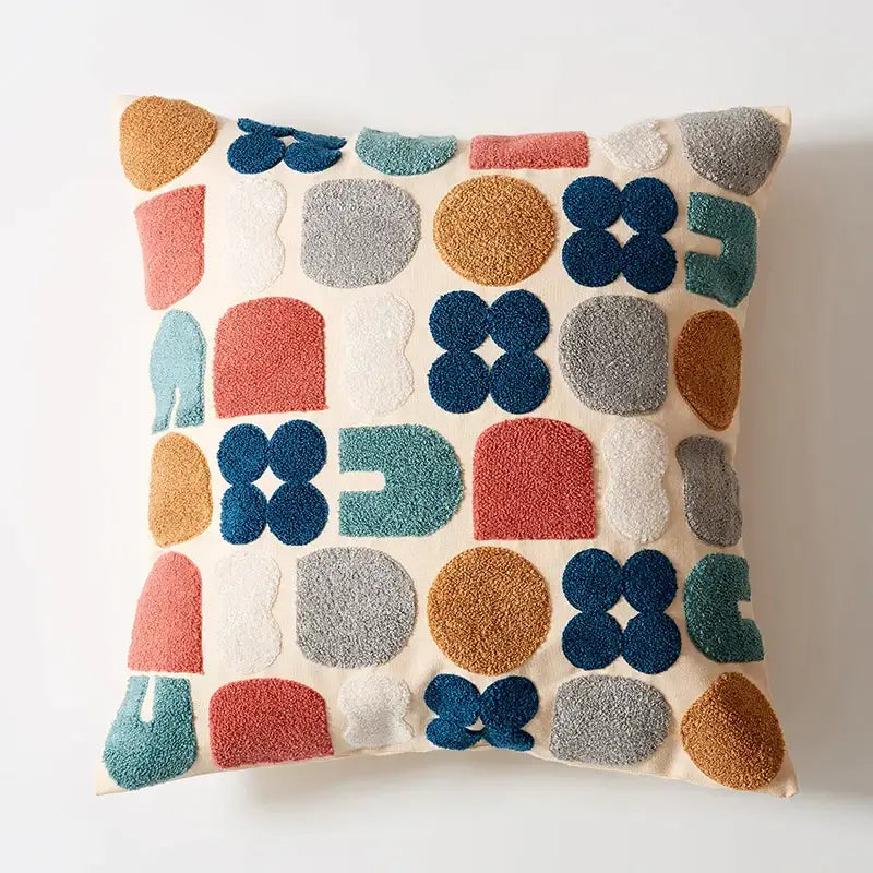 Cream-colored pillow cover with embroidered floral dot pattern and geometric plush shapes for home decor use