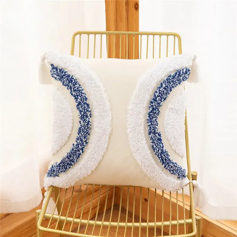 Cream-colored pillow cover with plush textured blue and white crescent moon embroidery and geometric leaves design