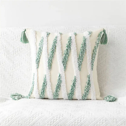 Cream-colored pillow cover with embroidered geometric leaves featuring green and white textured yarn stripes and tasseled corners