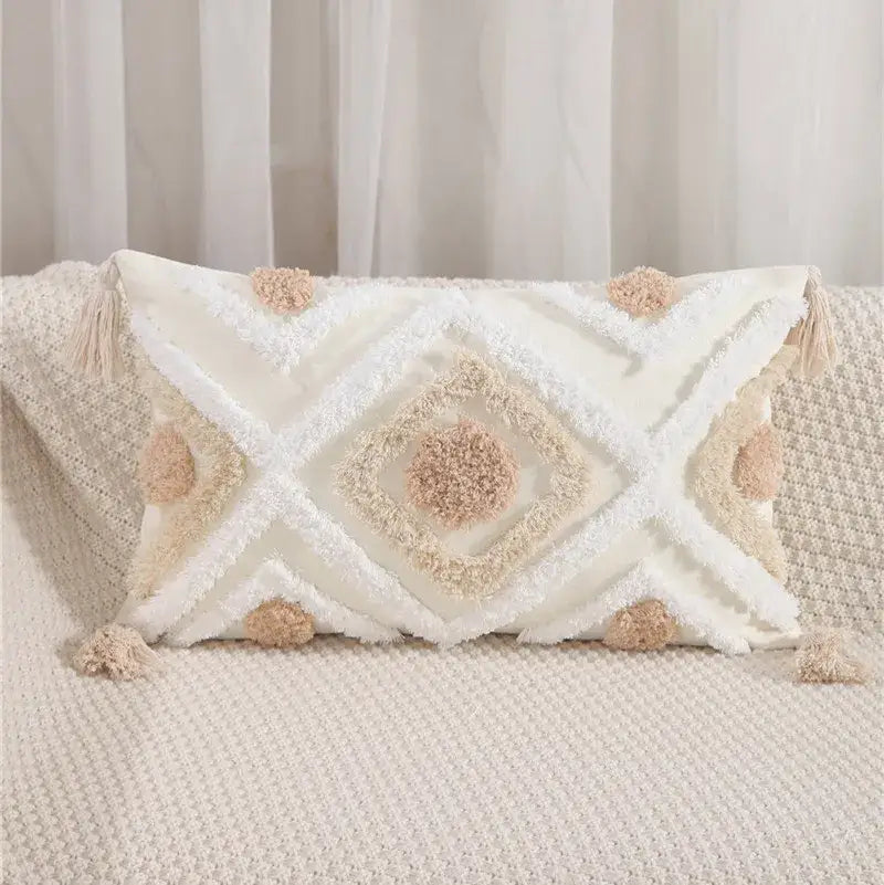 Cream-colored textured pillow cover with embroidered geometric leaves pattern and fluffy pom-poms for living room decor