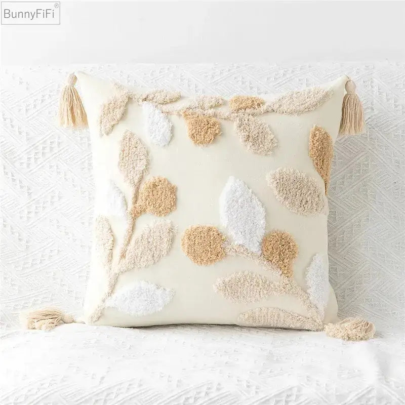 Cream-colored bunnyfifi pillow cover with embroidered geometric leaves and tasseled corners for living room decor