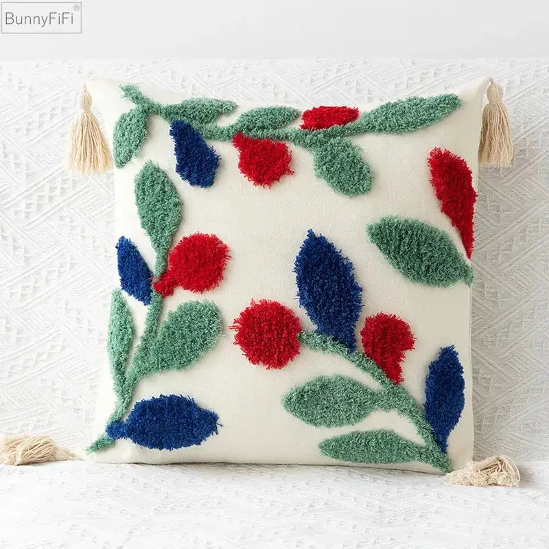 Cream-colored pillow cover with embroidered geometric leaves featuring red and blue berries and beige tassels for living room decor