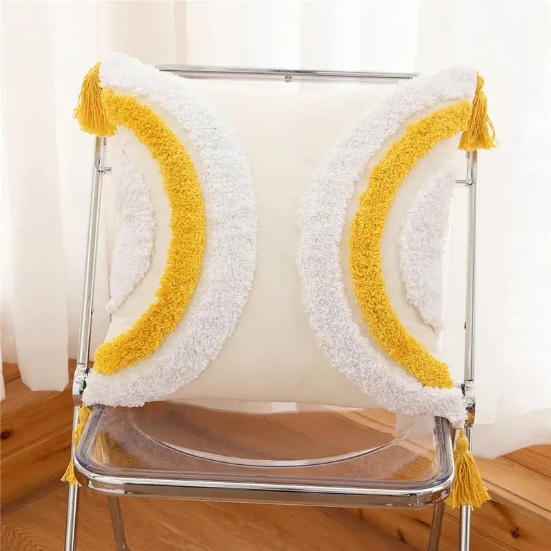 A cozy white and yellow pillow cover with embroidered geometric leaves and tassels featuring a plush crescent moon design