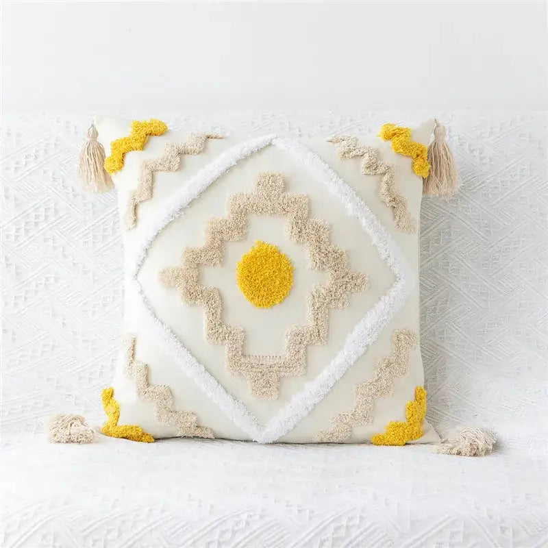 Cream-colored embroidered geometric leaves pillow cover with beige and mustard textured tassels for living room decor