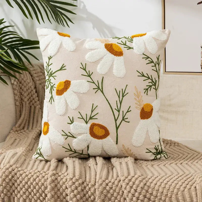 Cream-colored pillow cover with embroidered white daisies and green stems in soft fabric for living room decor