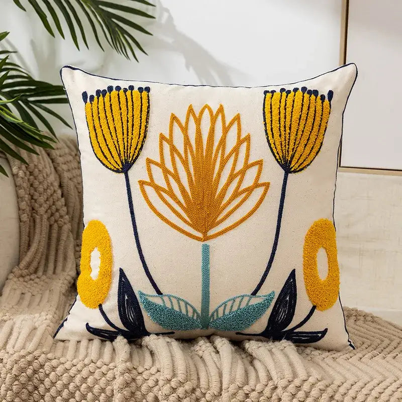 Cream-colored pillow cover with embroidered daisy yellow floral and teal flowers on navy stems for living room use