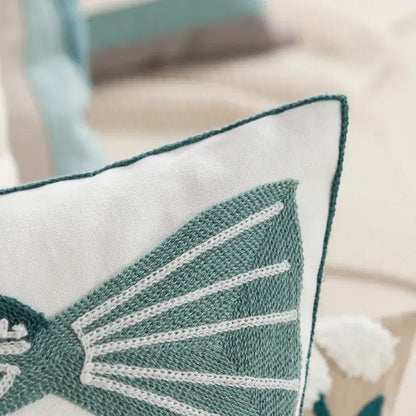 A white pillow cover with teal embroidered butterfly and white stitching complementing daisy yellow floral decor