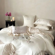 Cream-colored satin bedding set featuring delicate floral embroidery and ruffled edges in embroidered lace princess style