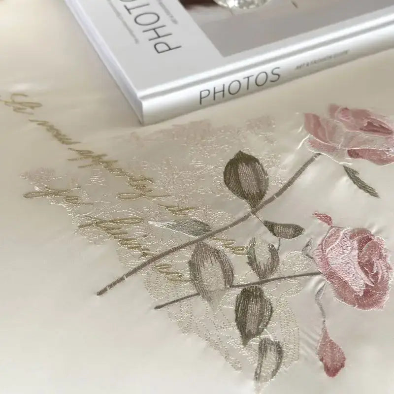 A cream embroidered lace princess bedding set featuring delicate pink roses and gold thread script for floral decor