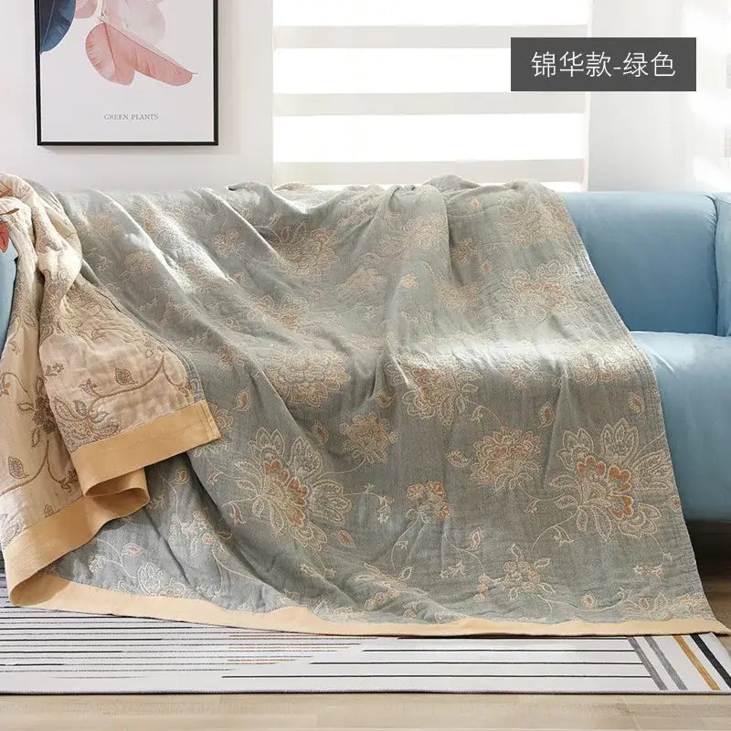 A sage green decorbites cotton gauze summer throw blanket with floral embroidery and a cream border for bedroom decor